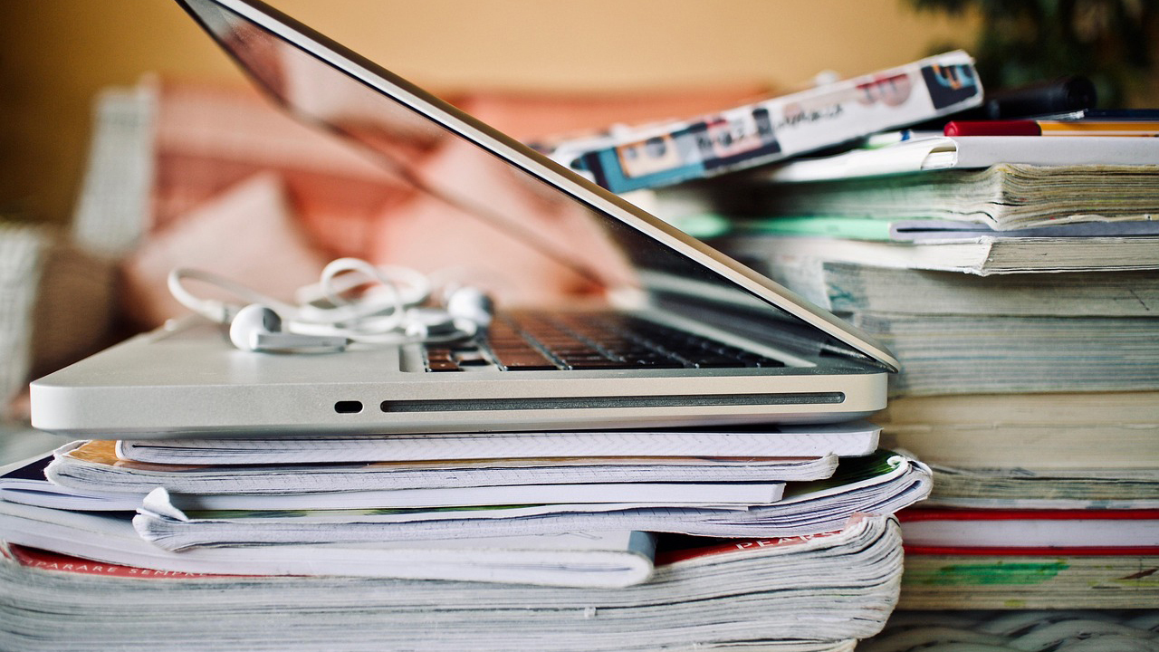 a laptop with headphones stacked on top of notebooks